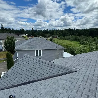 Completed gray shingle roofing project viewed across multiple roof sections